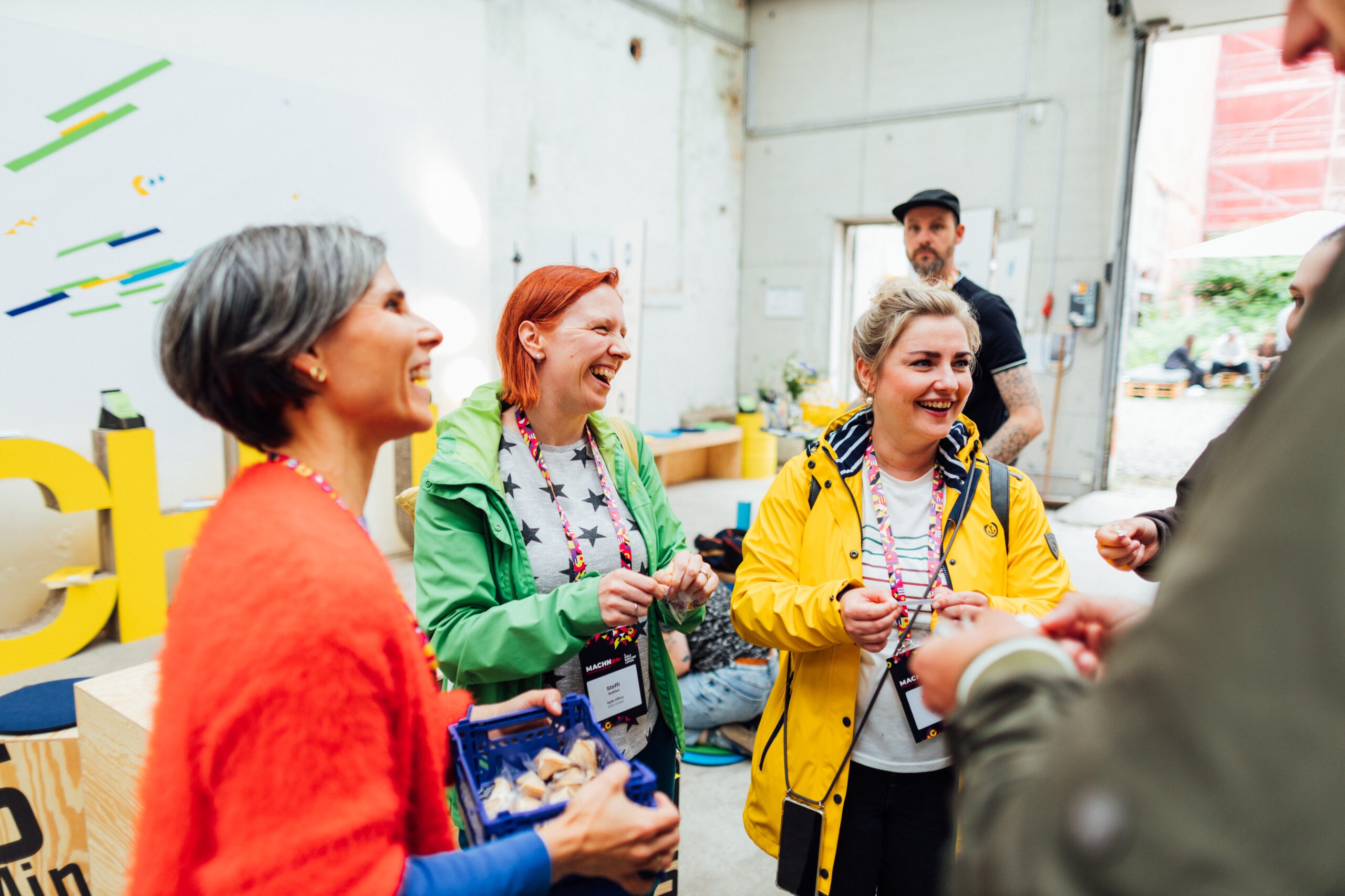 Drei Frauen in bunten Jacken lachen