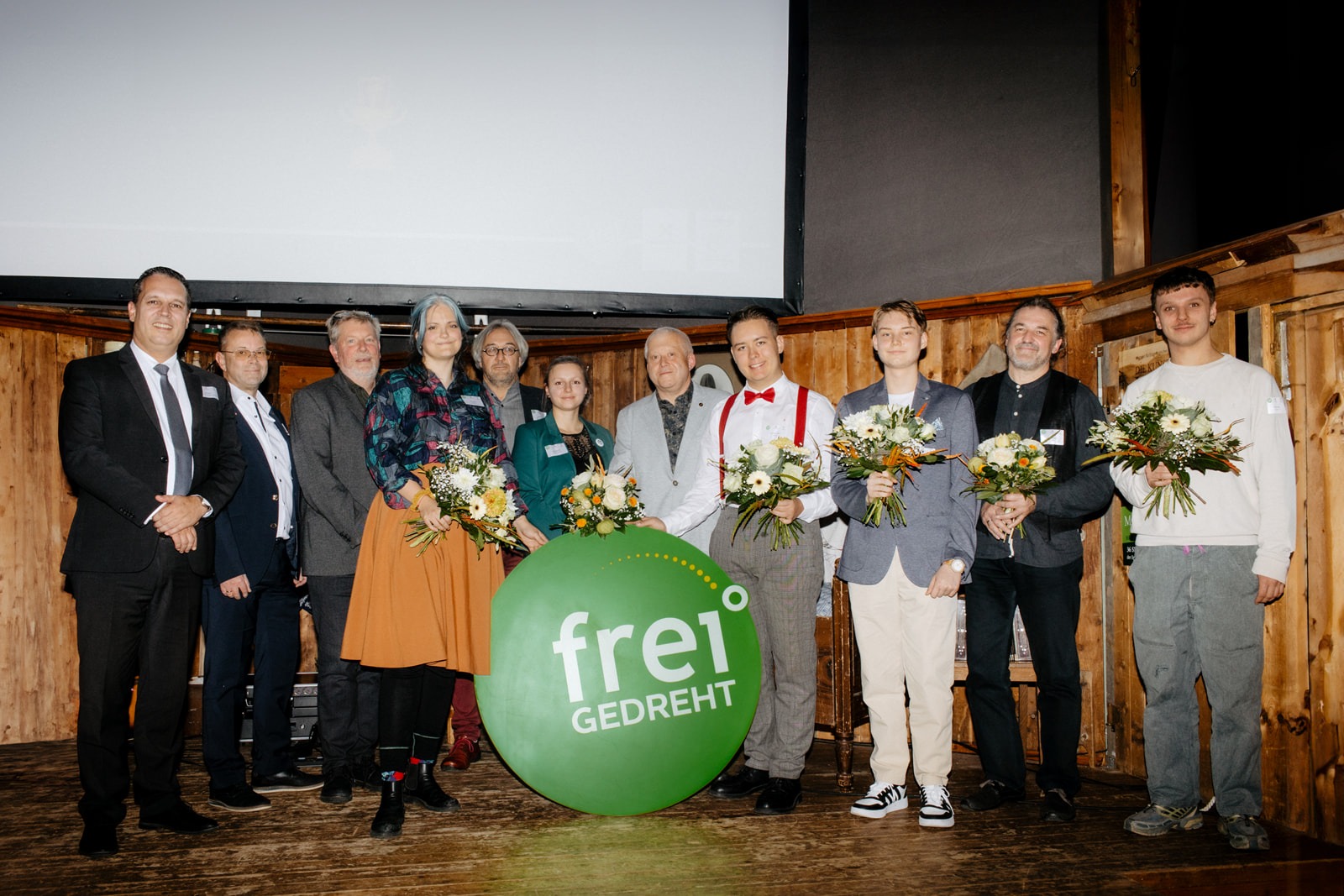 Gewinnerinnen und Jury auf einer Bühne, im Vordergrund das Logo des Wettbewerbs freiGEDREHT