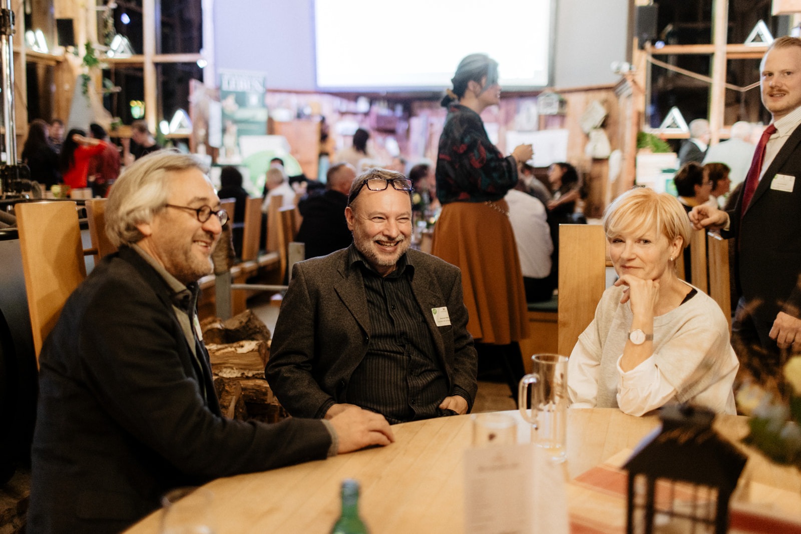 Zwei Frauen und ein Mann sitzen an einem Tisch und lachen
