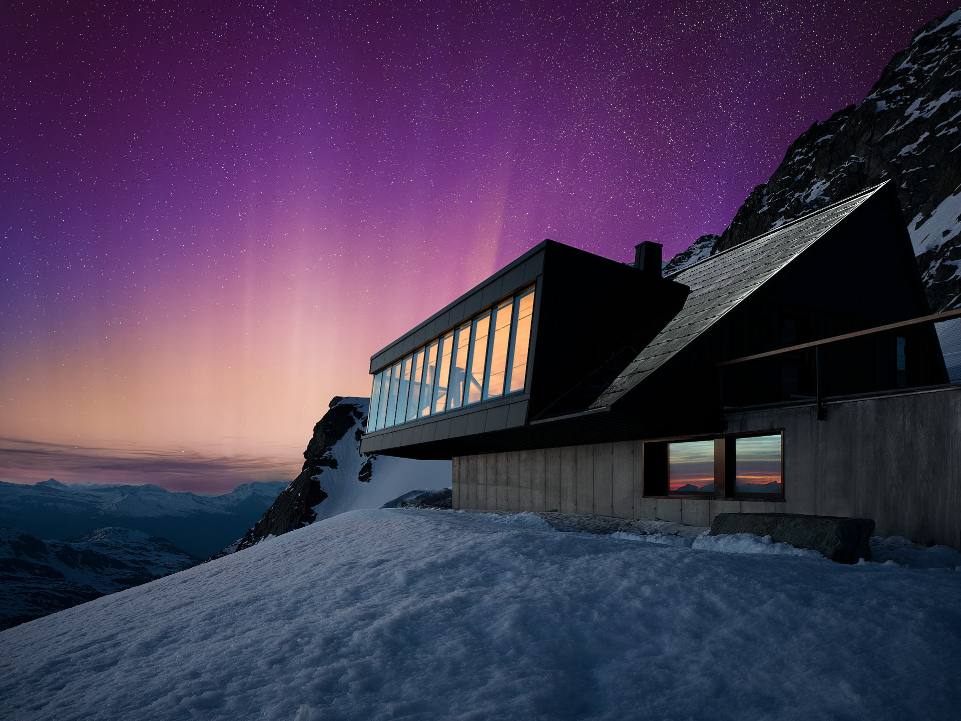 Eine Hütte mit großer Fensterfront im Schnee, im Hintergrund lila weiße Nordlichter