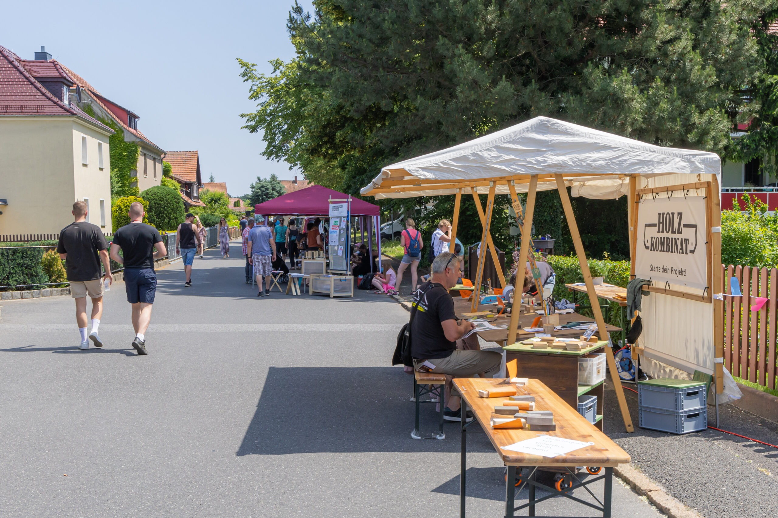 Ein Pavillion mit Bänken auf einer leeren Straße mit der Aufschrift Holzkombinat